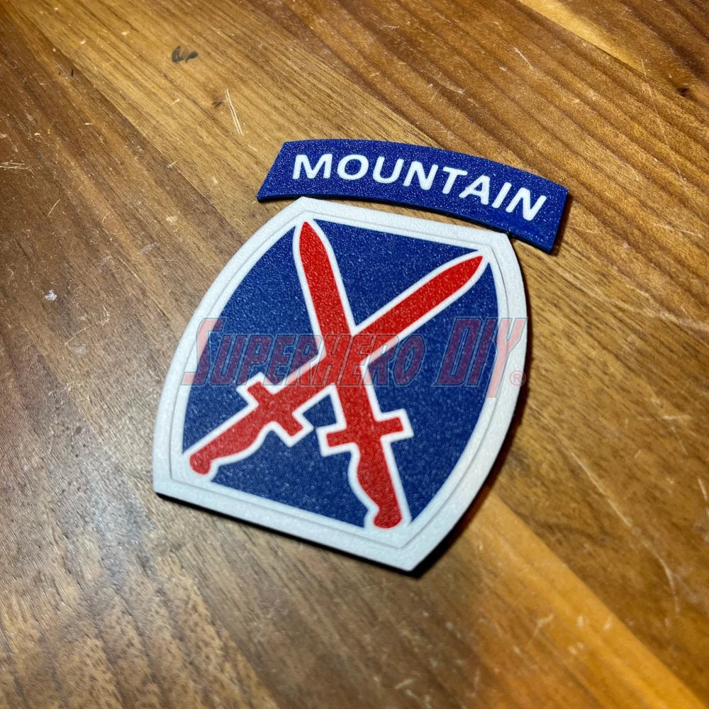 3D-printed 10th Mountain Division insignia with blue, red, and white design, displayed on a wooden surface.