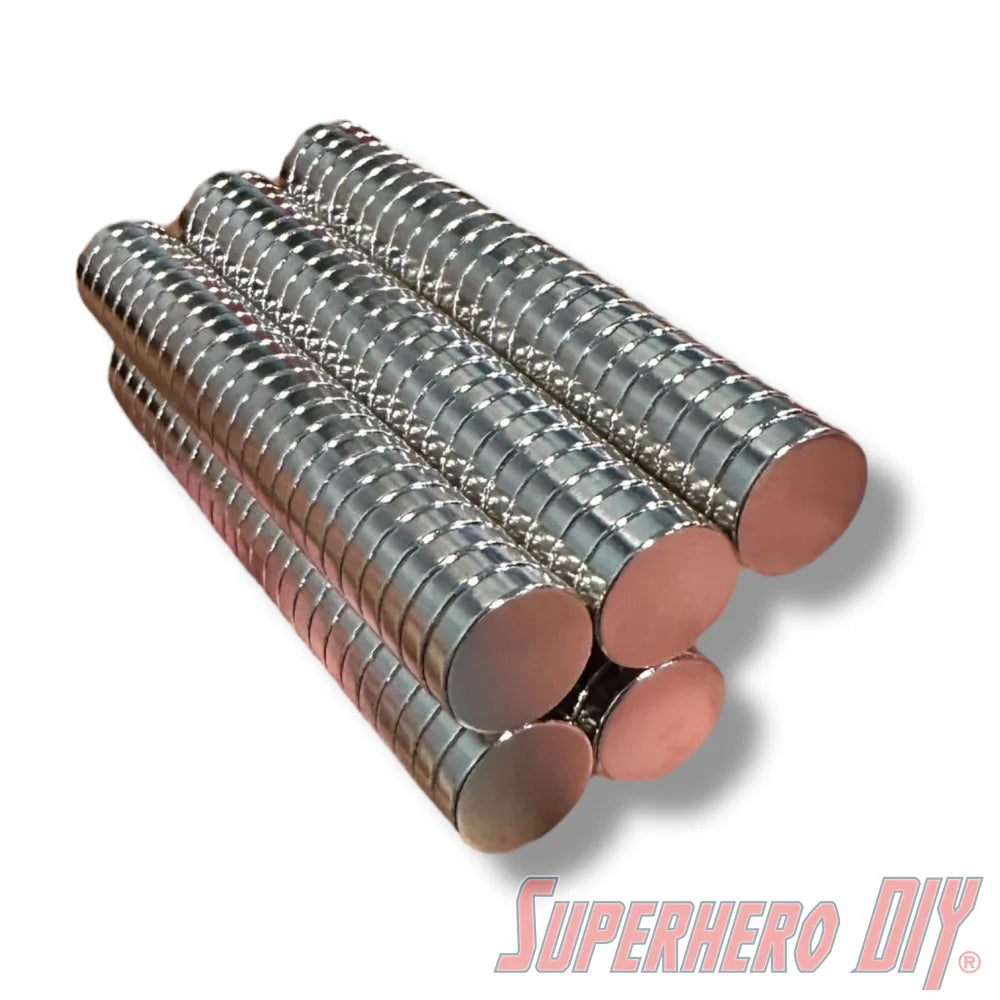 Stacks of shiny silver neodymium disc magnets arranged in cylindrical columns on a white background. - SuperheroDIY