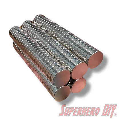 Stacks of shiny silver neodymium disc magnets arranged in cylindrical columns on a white background. - SuperheroDIY