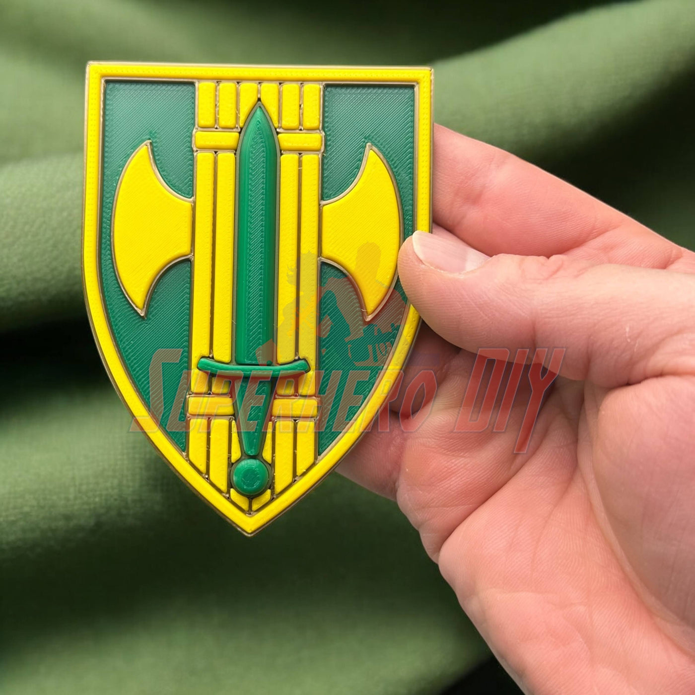 Hand holding 18th Military Police Brigade Display Insignia with green and yellow design on fabric background.