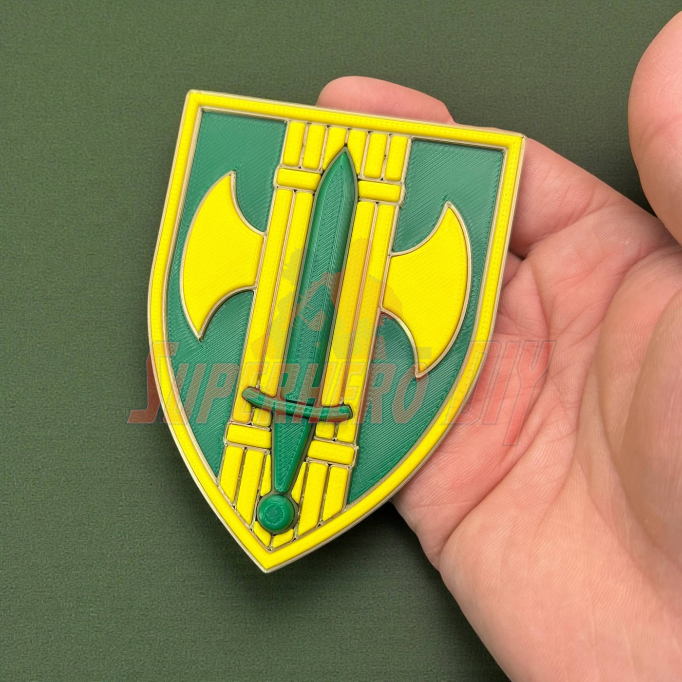 Hand holding 18th Military Police Brigade Display Insignia, green and yellow shield design.