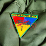 1st Armored Division display insignia featuring Old Ironsides patch on green fabric background.
