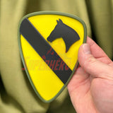 Close-up of 1st Cavalry Division Display Insignia held in hand, showcasing the distinct yellow and black design.