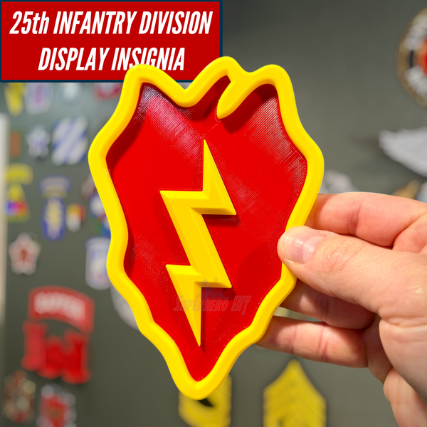 Hand holding a 25th Infantry Division taro leaf display insignia in front of a wall of military insignia displays