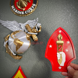2nd Marine Division display insignia held next to Marine Corps emblem, showcasing vibrant colors and detailed design.