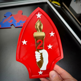 2nd Marine Division display insignia featuring a red shield with a torch and stars, representing the 2nd Marines.