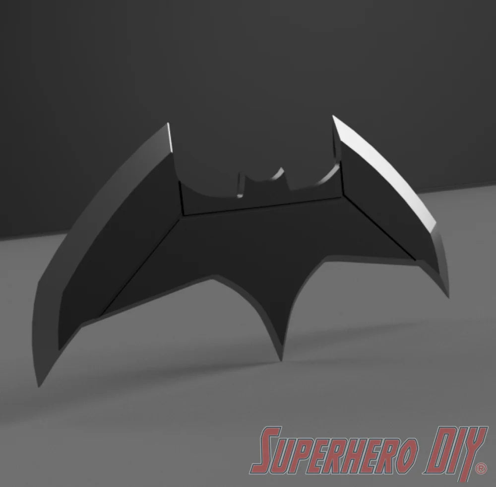 Black bat-shaped object with angular wings and a small bat emblem in the center on dark background. - SuperheroDIY