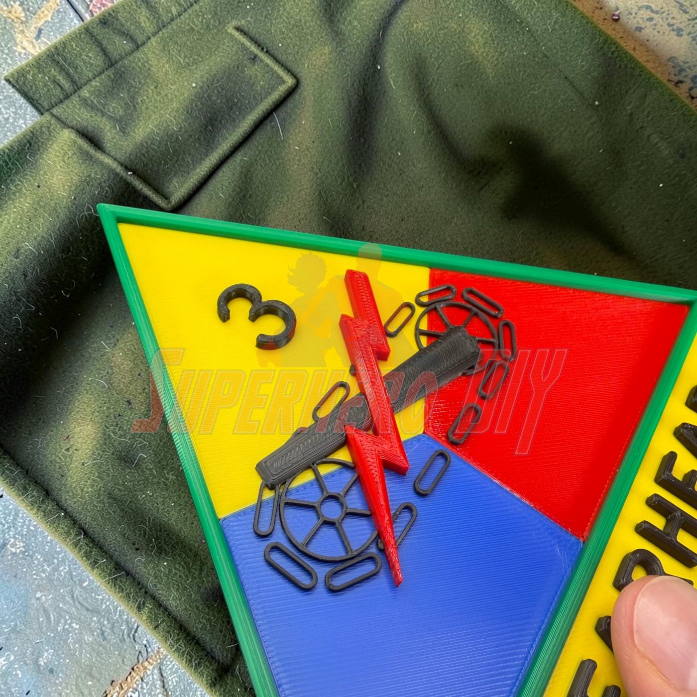 3rd Armored Division display insignia showcasing the Spearhead design on a green fabric background.
