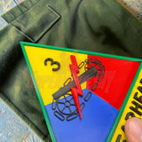 3rd Armored Division display insignia showcasing the Spearhead design on a green fabric background.