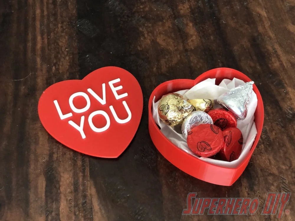 3D-PRINTABLE STL FILE | Candy Heart Gift Box | DIGITAL FILE ONLY - Red heart-shaped gift box with removable lid reading "LOVE YOU" in white, filled with assorted chocolates and candy hearts. - SuperheroDIY