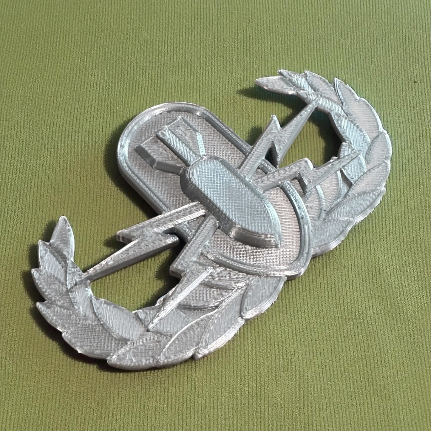 Replica EOD Badge Display showing detailed ornamentation on a green background