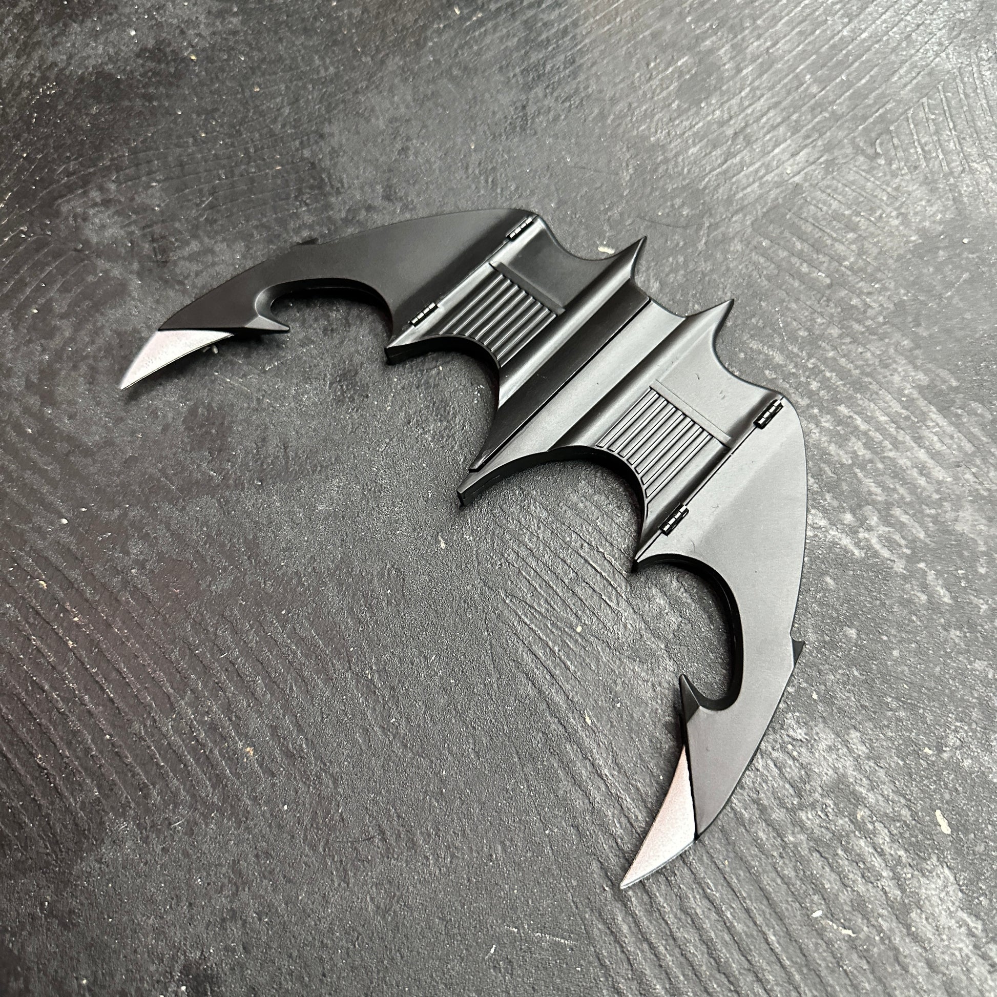 NECA BATMAN 1989 Folding Magnetic Batarang (LOOSE) displayed on a black surface, showcasing its sleek design.
