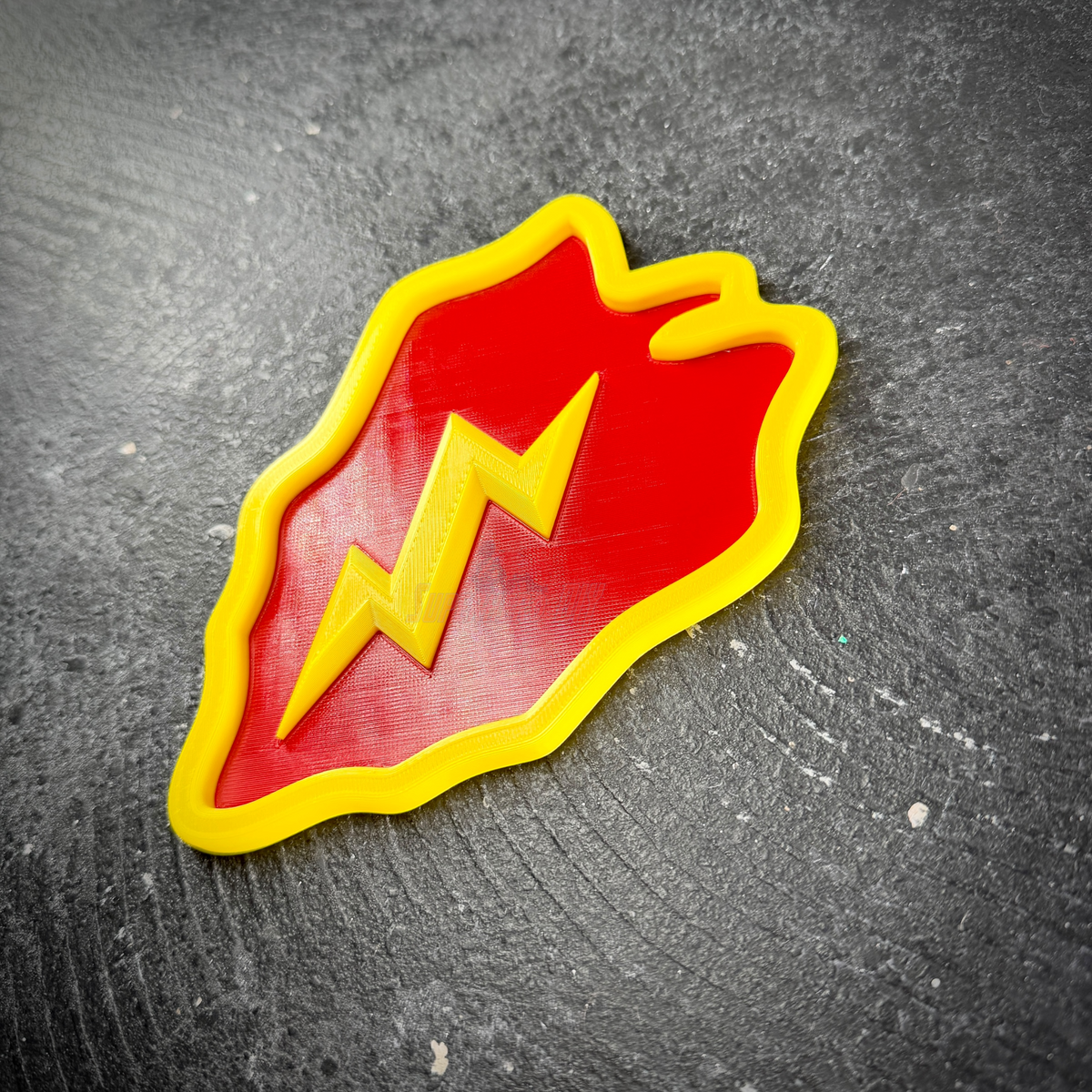 Side angle of the Tropic Lightning taro leaf insignia showing the raised yellow border and bolt in layered relief