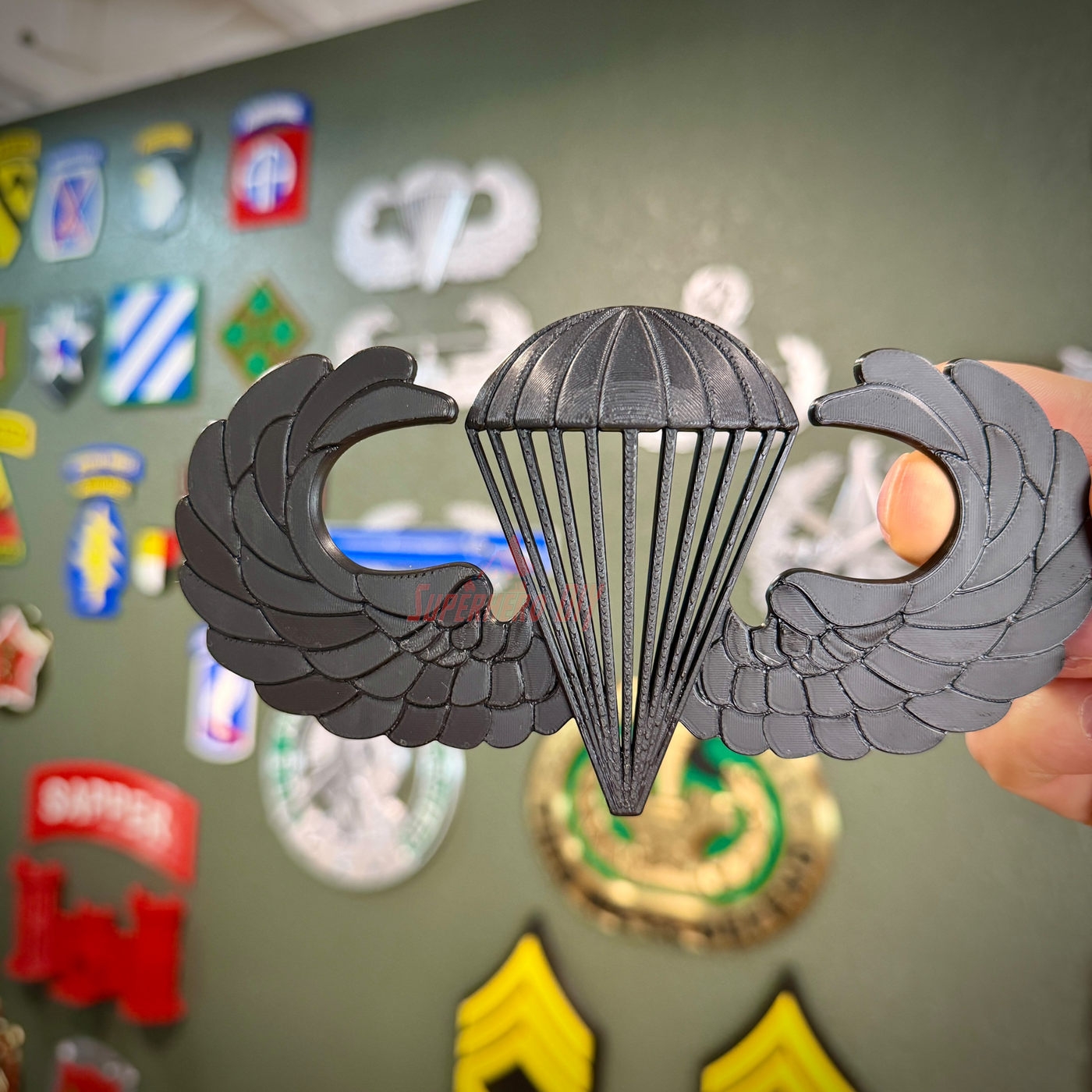 Airborne jump wings badge displayed against a background of military insignia and patches.