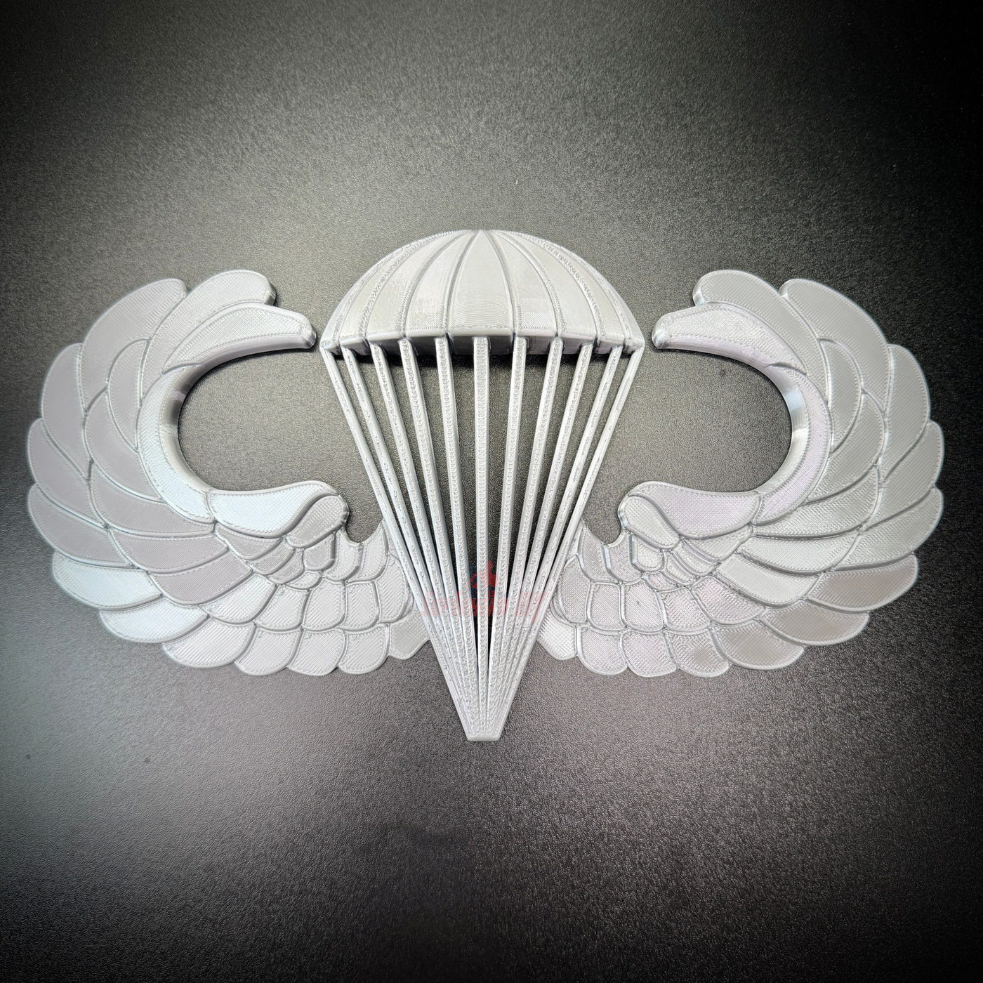 Airborne jump wings badge with parachute and wing design, representing airborne achievement and military service.
