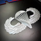 Airborne jump wings badge displaying detailed silver design with wings and parachute, symbolizing airborne achievement.