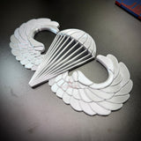 airborne jump wings badge replica displayed on a dark surface, showcasing its detailed design and craftsmanship.