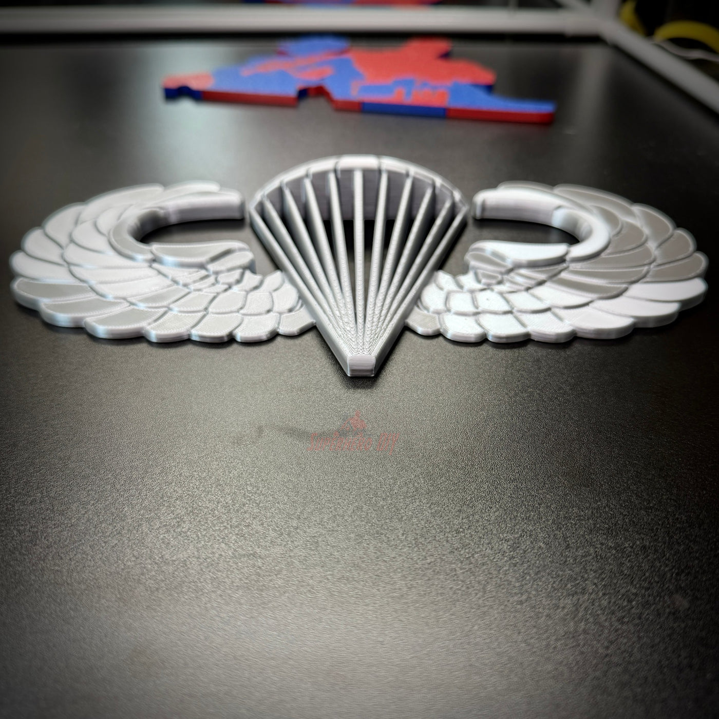 airborne jump wings badge displayed on a black surface, symbolizing military parachutist achievement.