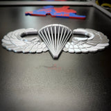 airborne jump wings badge displayed on a black surface, symbolizing military parachutist achievement.