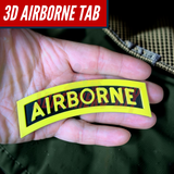 3D airborne tab resting in a hand, featuring bold yellow lettering on a solid black background.