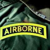 3D airborne tab displayed on fabric background with bold yellow lettering and black border