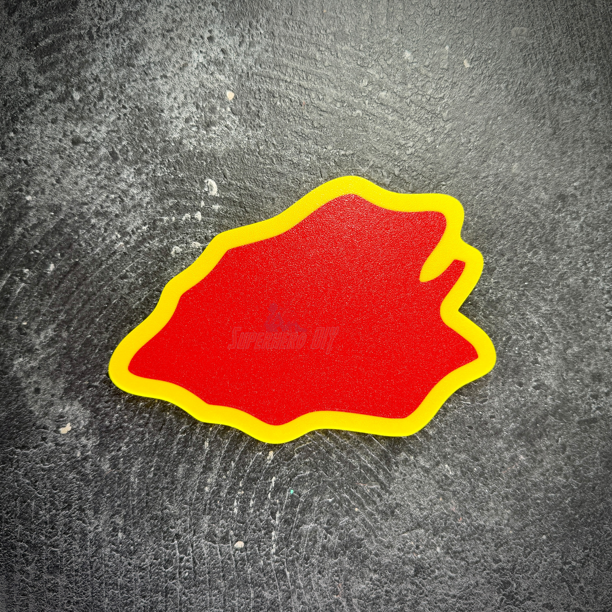 Flat back of the 25th ID taro leaf display insignia, red with a yellow edge, ready for adhesive strip mounting