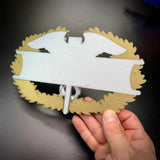 Hand holding an army medical badge display insignia featuring gold and silver elements, ideal for showcasing achievements.