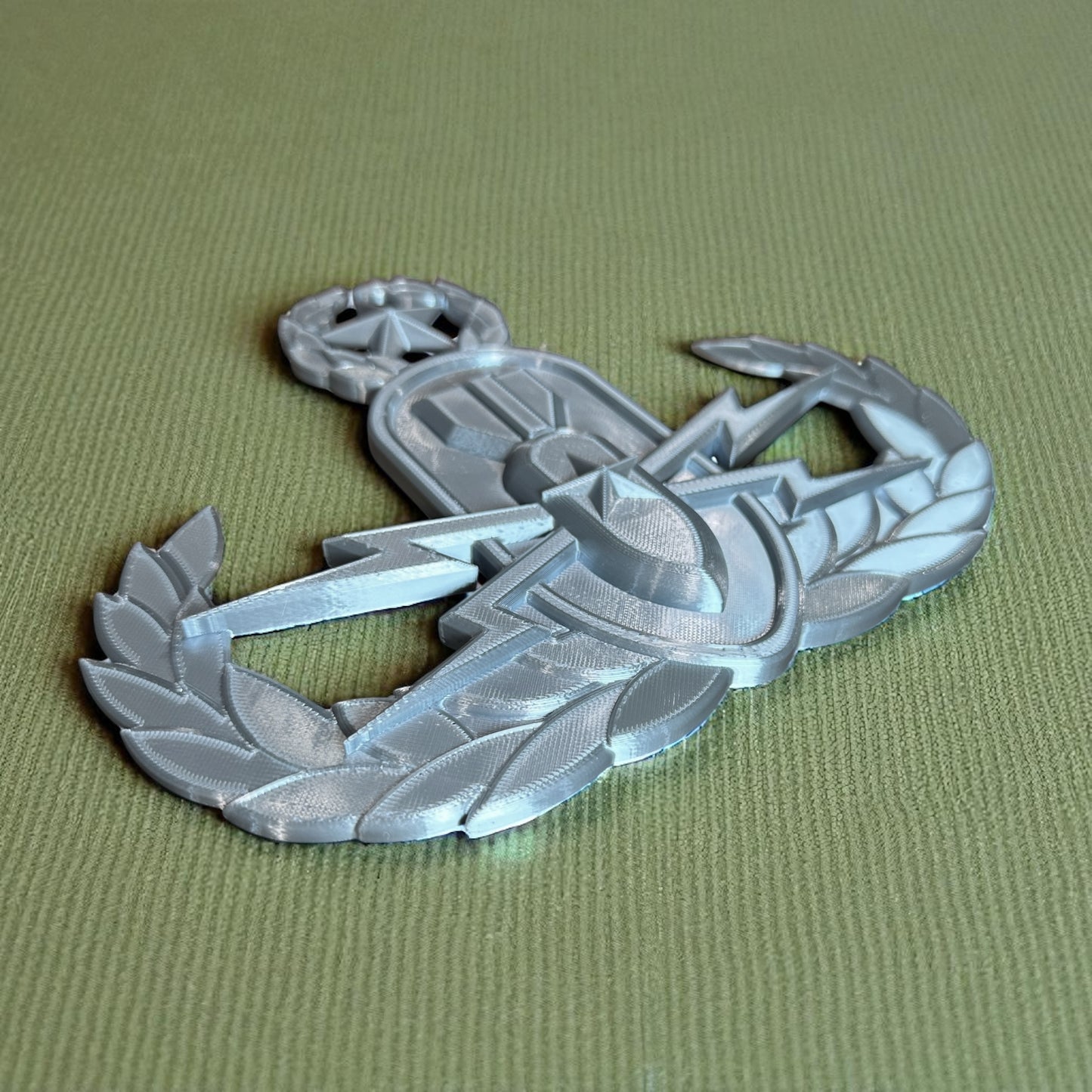 Replica EOD Badge Display showcasing basic, senior, and master levels on a textured green background.