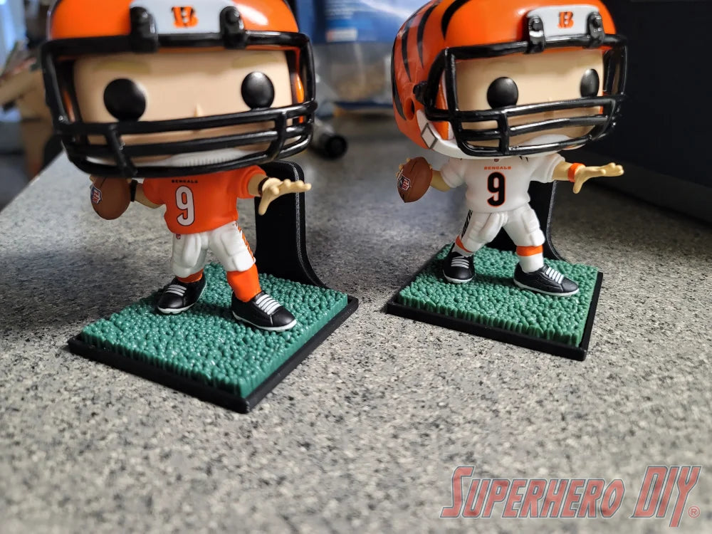 Two football-themed Funko Pop figures in orange helmets on green grass-textured floating shelves with black square bases. - SuperheroDIY