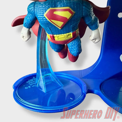 Blue floating shelf with clear support stand holding Superman Funko Pop figurine. - SuperheroDIY