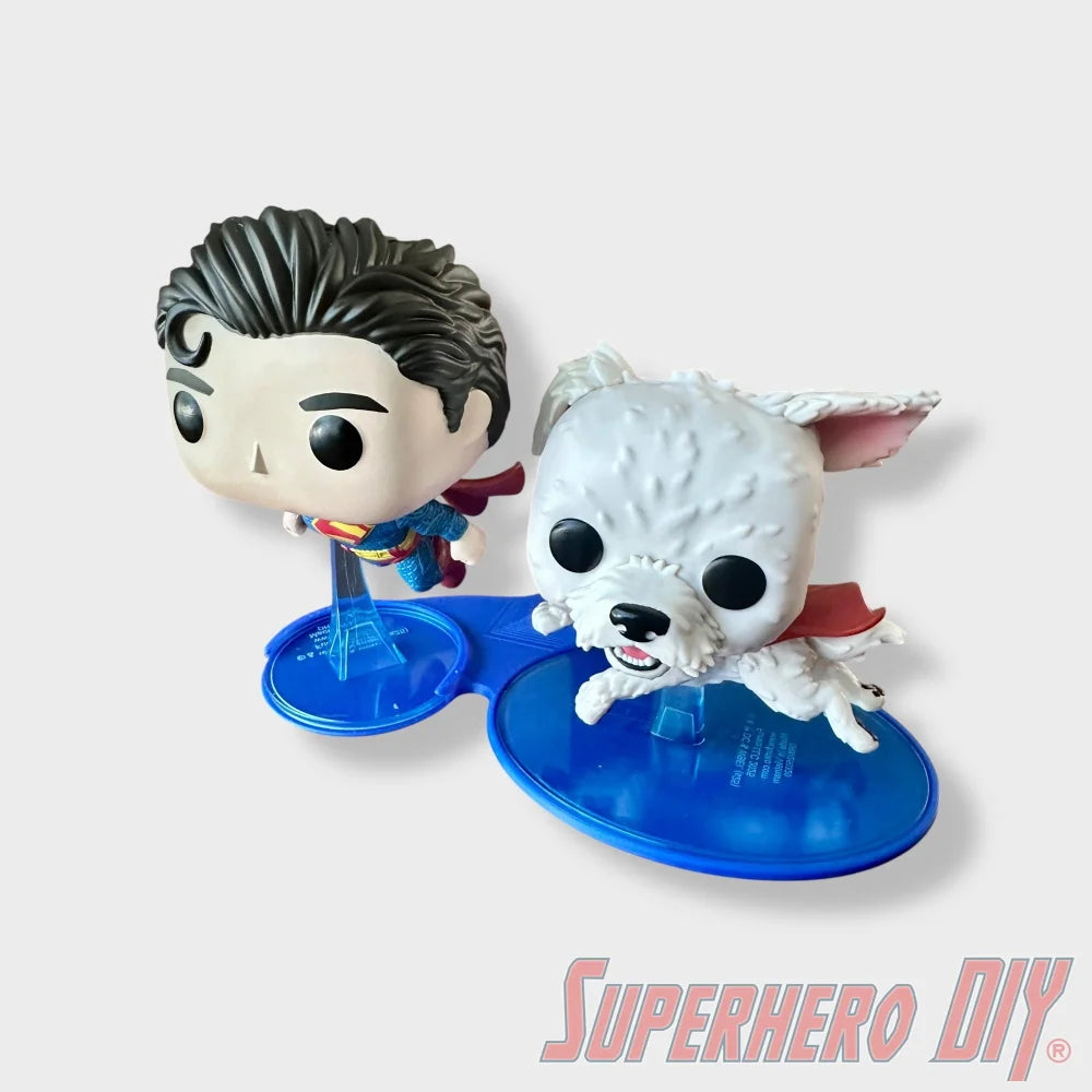 Blue floating shelves holding Superman Funko Pop #562 and Krypto Funko Pop #565 figures on a white background. - SuperheroDIY