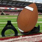 Black wall mount holder securely cradling a brown football with white stripes on a football field background. - SuperheroDIY