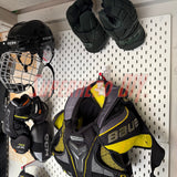 Hockey gear including a helmet, gloves, and shoulder pads hanging on a IKEA skadis pegboard.