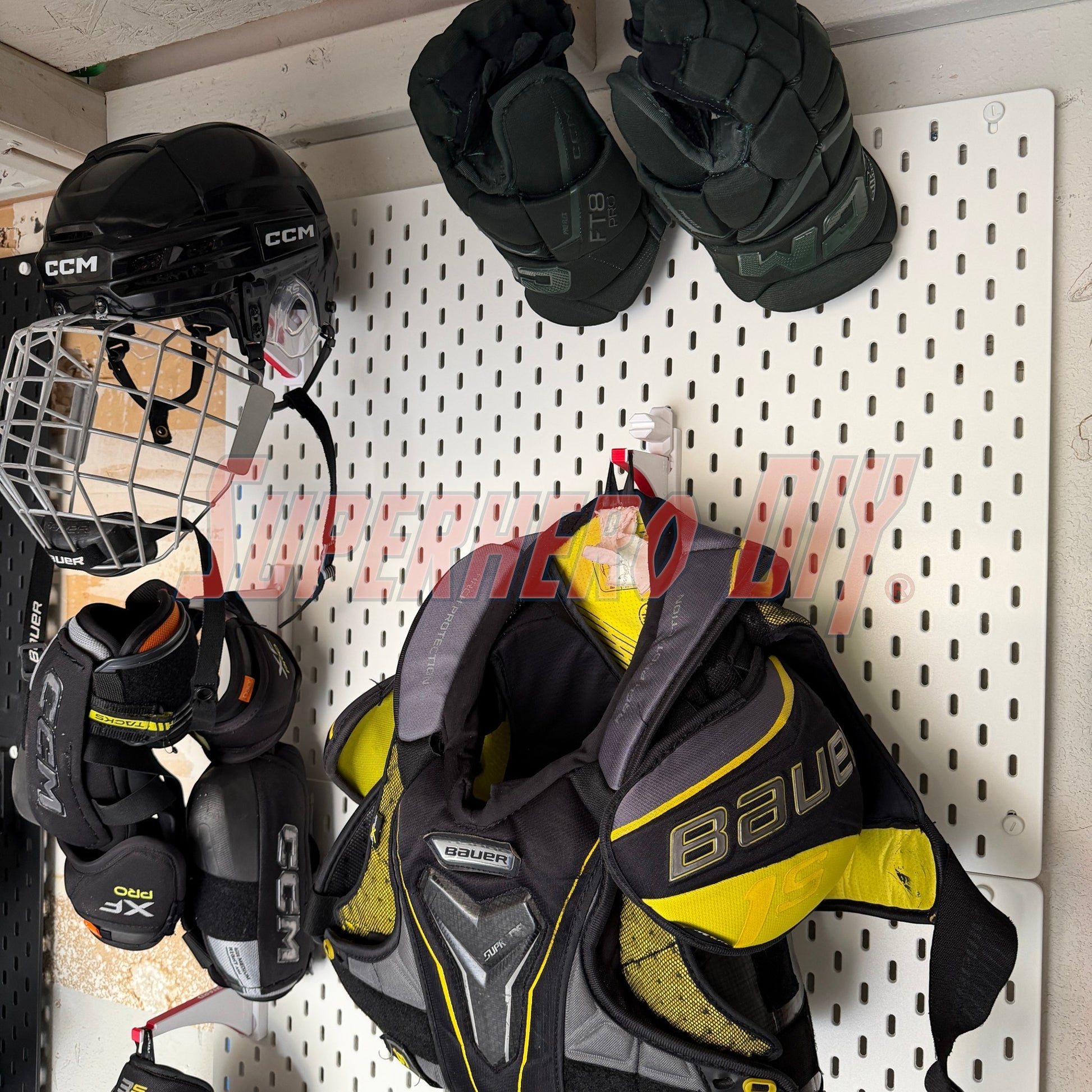 Hockey gear including a helmet, gloves, and shoulder pads hanging on a IKEA skadis pegboard.