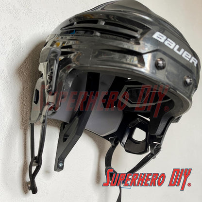 Black hockey helmet with 'Bauer' branding mounted on a white wall, featuring 'Superhero DIY' text.