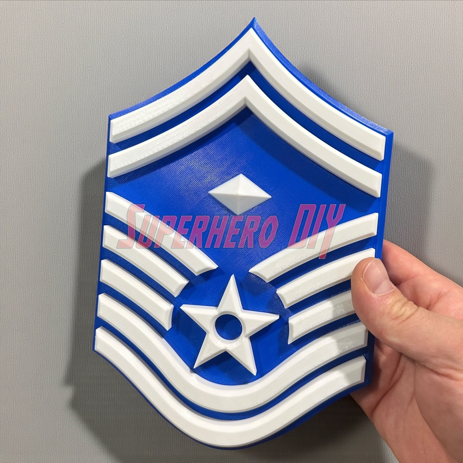 3D Air Force Enlisted Rank insignia held against a grey background, showcasing bold design and multiple sizes available for display.