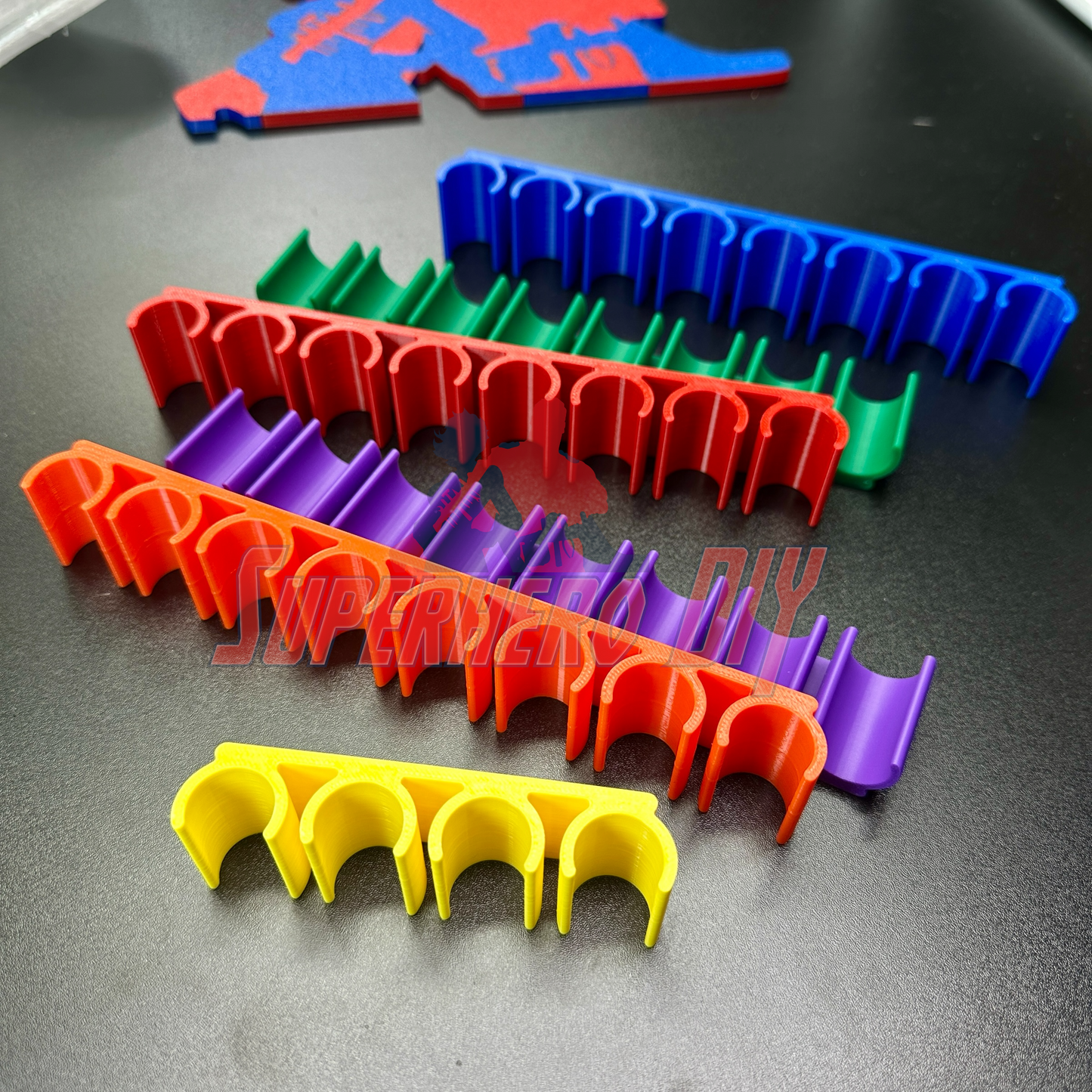 Colorful wall-mount dry erase marker holders in yellow, red, purple, green, and blue, each with multiple slots. - SuperheroDIY