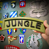 A hand holding a 3D jungle tab display piece with black lettering on an army green background.