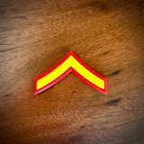 USMC Private First Class (E-2) single chevron rank insignia lying on a wood surface