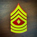 USMC First Sergeant (E-8) rank insignia with center diamond, three chevrons and three rockers, on a wood surface