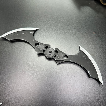 MAGNETIC Folding Arkham Batarang Cosplay Prop - 10" version, laying open on a dark surface, showcasing its dual blades and central hinge.