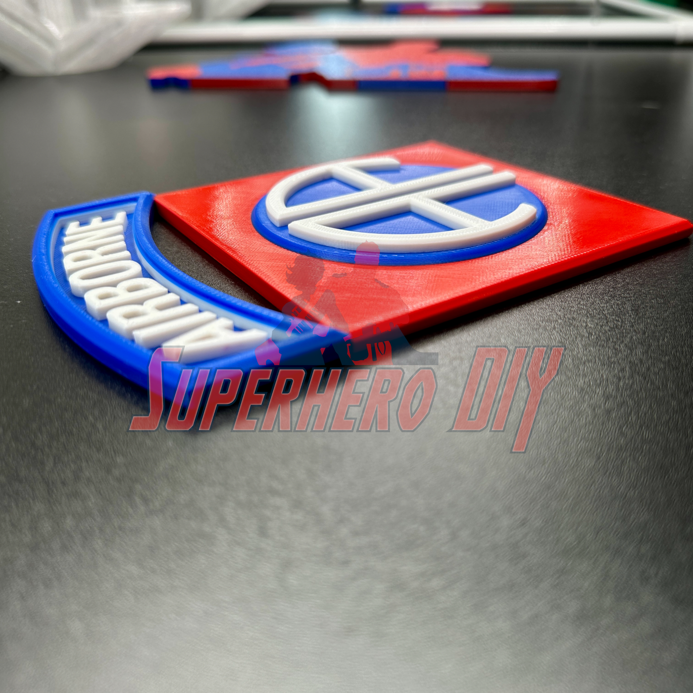 3D-printed 82nd Airborne Division display insignia in red and blue, showcasing the AA symbol on a smooth black surface.