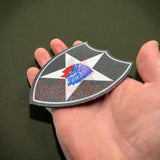 Hand holding 3D-printed 2nd Infantry Division display insignia patch for military shadowbox or wall display.