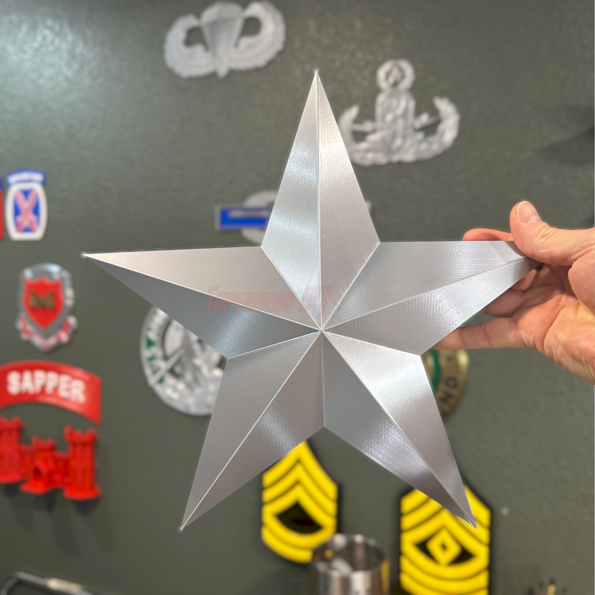 Silver star-shaped Brigadier General Rear Admiral rank insignia replica held by a person, showcasing its glossy finish.