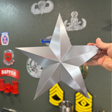 Silver star-shaped Brigadier General Rear Admiral rank insignia replica held by a person, showcasing its glossy finish.