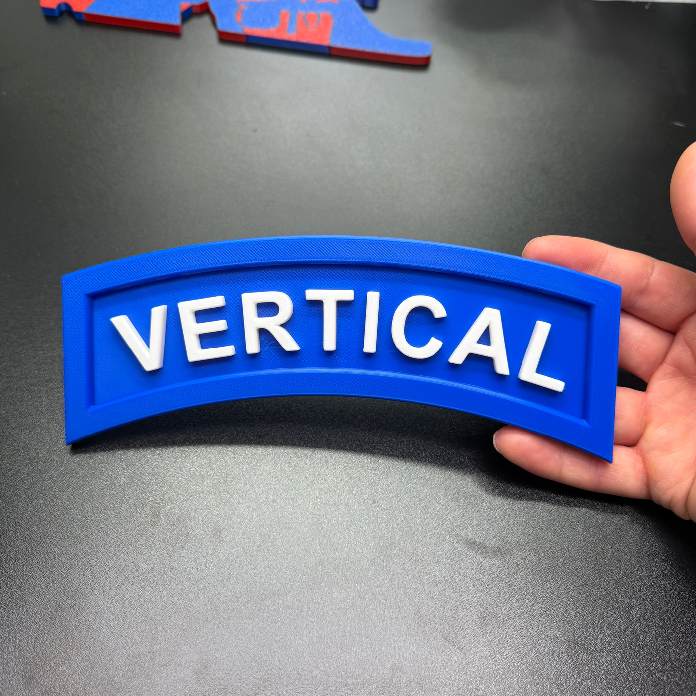 3D vertical construction engineer tab in blue with white letters spelling VERTICAL