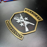 Image of Bradley Master Gunner Badge display with crossed weapons and stars in bold relief.
