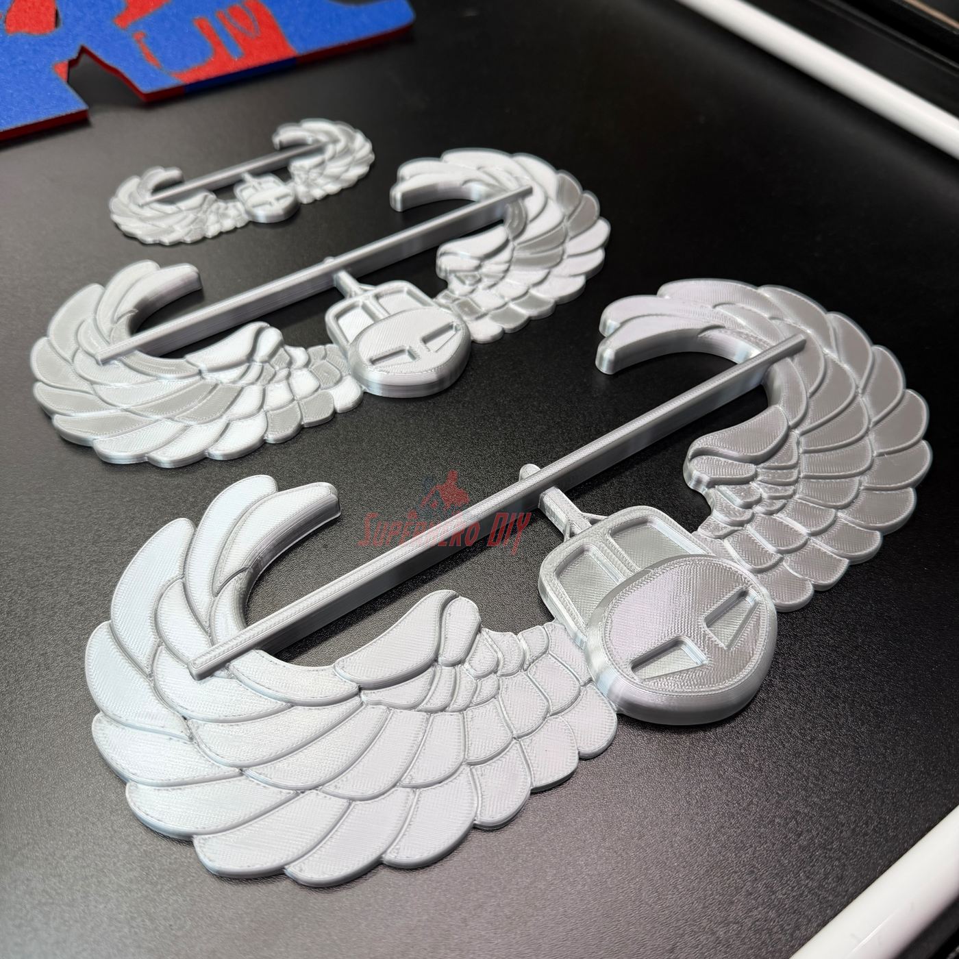 Air Assault Badge display insignia pieces featuring shiny silver wings and secure fasteners.