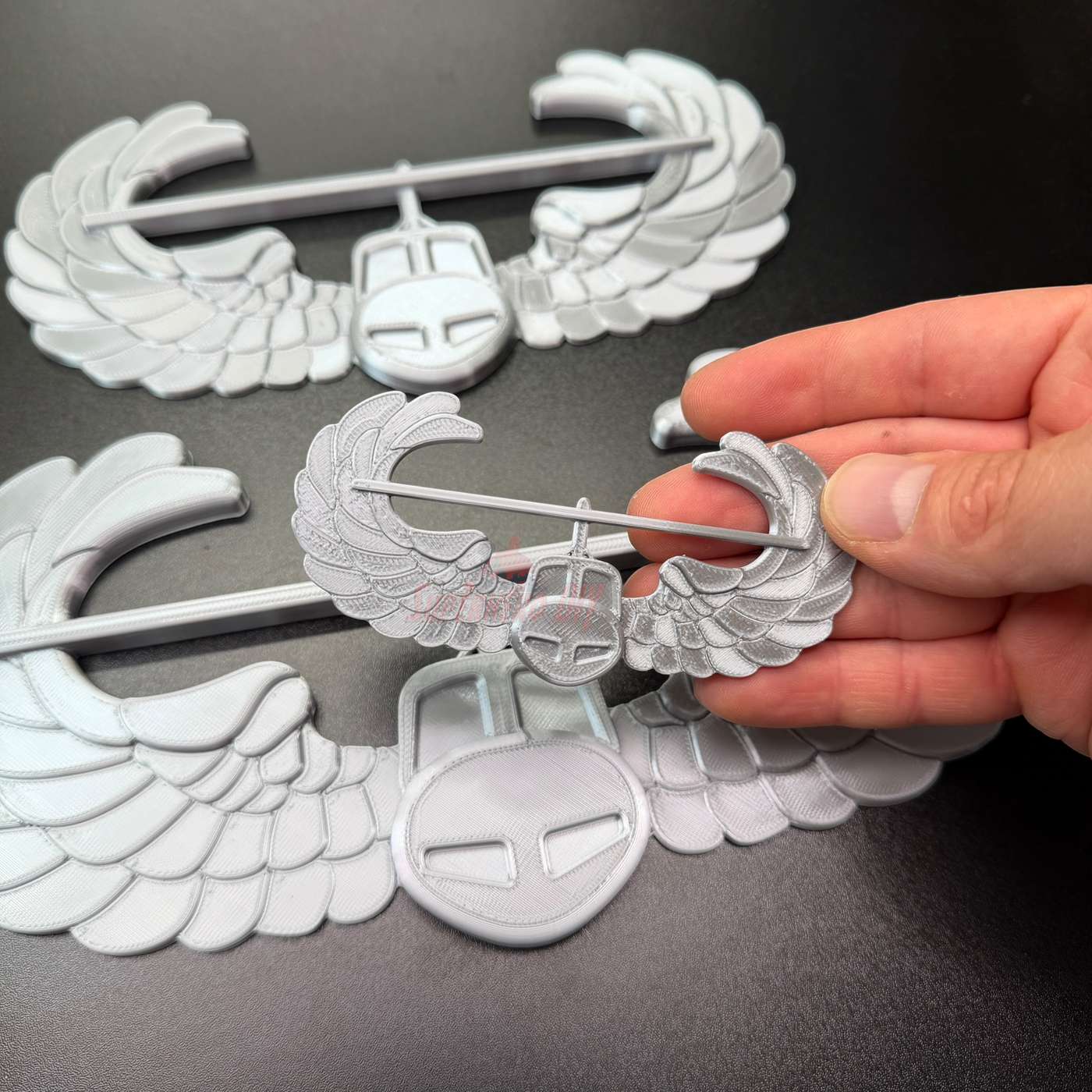 Air Assault Badge display with shiny silver finish, showcasing military insignia in hand.