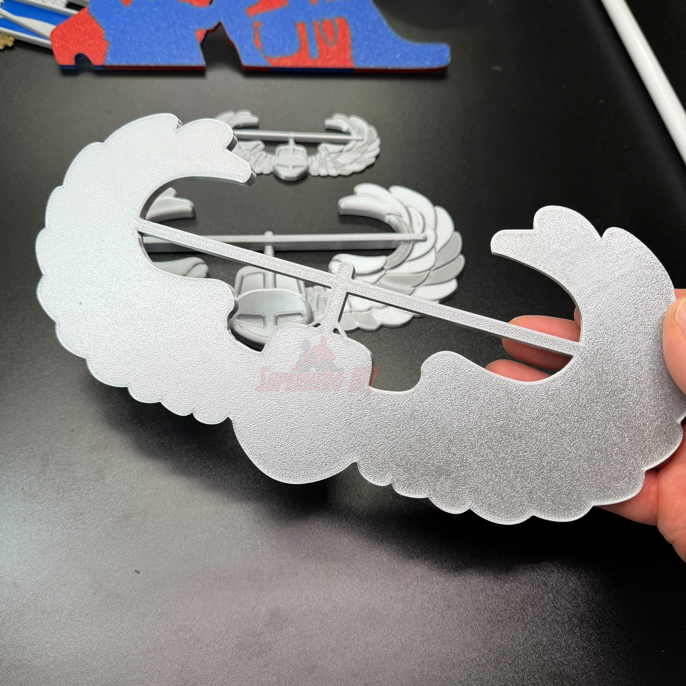 Air Assault Badge display piece in shiny silver finish held by hand for military insignia showcase.